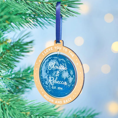Decorative ornament with text on a Christmas tree with blurred lights in the background