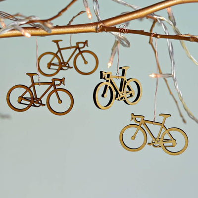 Bamboo bicycle-shaped decorations hanging from a branch with lights on a light blue background