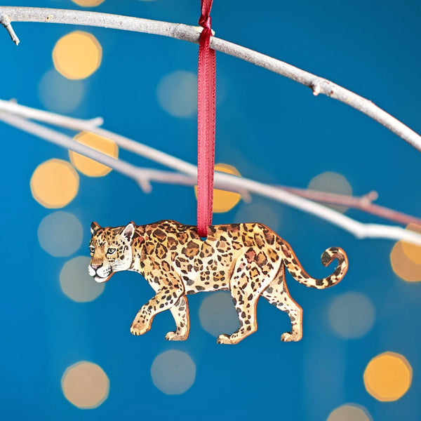 Leopard ornament hanging from a branch with a blurred festive background