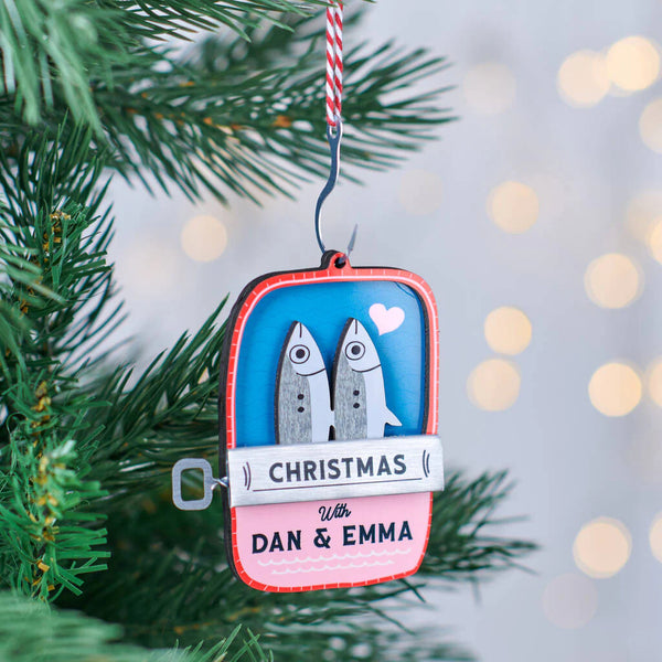 Decorative Christmas ornament with fish design and personalized text, hanging on a tree.