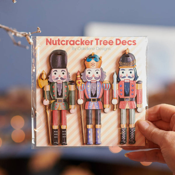 Packaged Nutcracker Tree Decs with a hand holding it against a blurred background